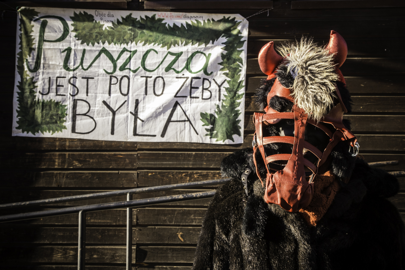 Diabeł pod budynkiem starej szkoły w Teremiskach na tle napisu Puszcza jest po to, żeby była.
